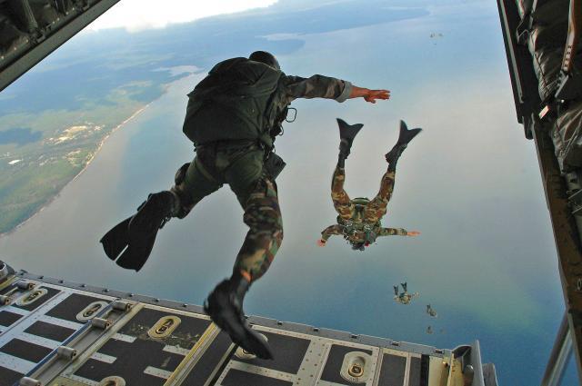 Soldiers jumping out of plane into the sky.