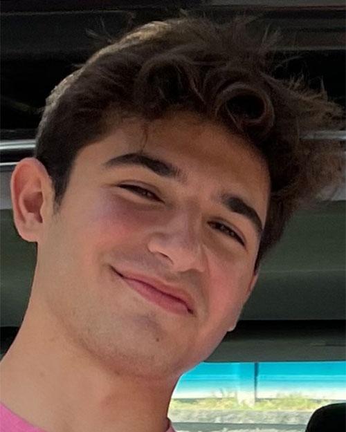 Photo of Ray Feinleib smiling at the camera. He has dark brown hair and is wearing a pink t-shirt