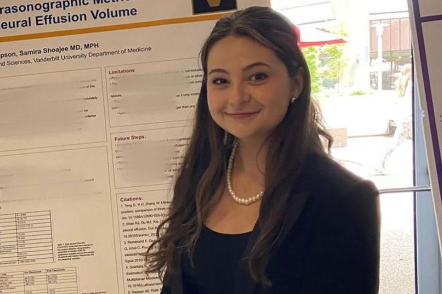 Altea Thompson is smiling at the camera while posing by a science presentation board