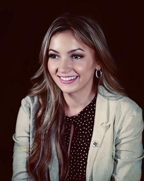 A woman wearing a white jacket and a black shirt, smiling