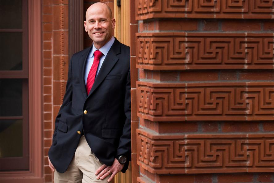 Frank Sobchak smiling in a suit and tie by a brick wall