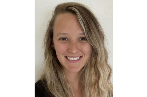 Photograph of Casey O’Reilly. Casey is smiling at the camera against a plain, white background. Casey has long, wavy, blonde hair and brown eyes. 
