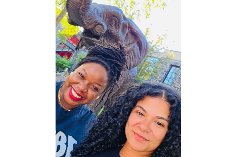 Two women smiling in front of an elephant statue